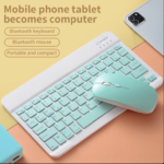 Clavier Bluetooth et souris sur une surface colorée, avec un smartphone en arrière-plan.