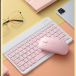 Clavier et souris rose sur un fond pastel avec des accessoires.